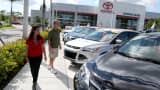 A salesperson (left) shows vehicles to a shopper at a Toyota dealership.